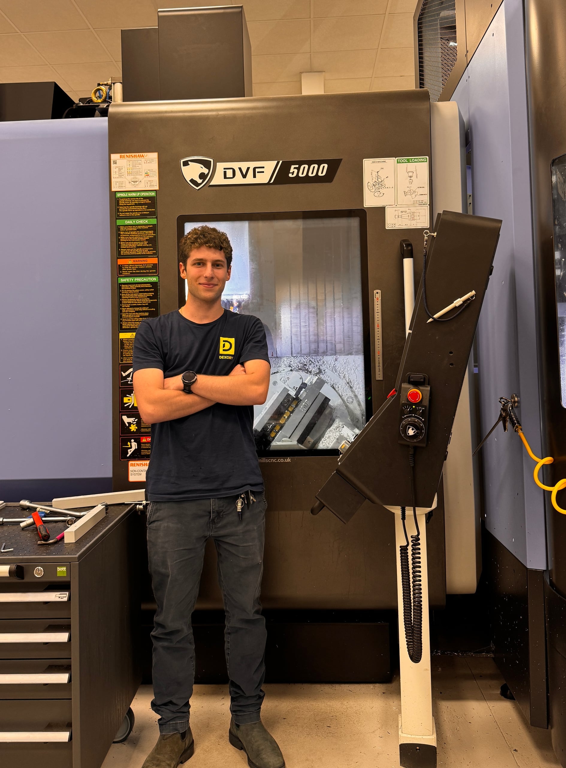 Liam Boone standing beside the Fanuc 5-axis CNC mill at Dexory during upright machining